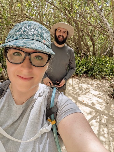 Ariele takes a selfie while hiking on a beach trail in Puerto Rico with Stephen and mangroves in the background